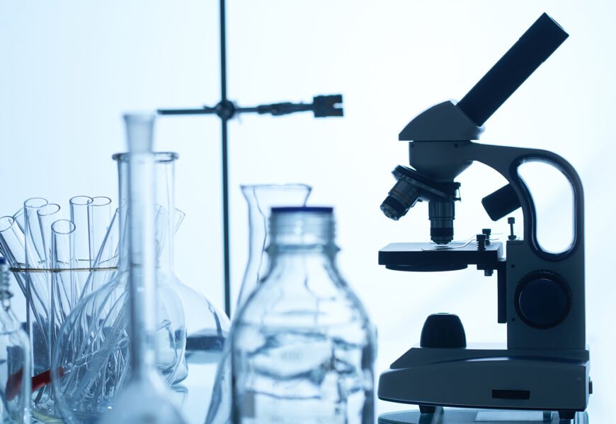 Laboratory Bench with Glassware and Equipment Laboratory bench with modern microscope, test tubes, glass bottles and flasks, white background
